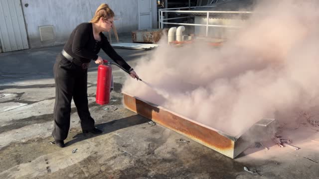 Female employee is training to use fire extinguisher at the fire drill