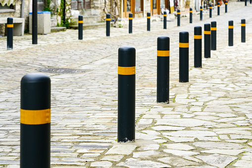 protection of a paved sidewalk from the driveway with black and yellow posts