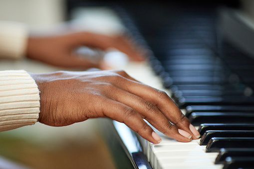 Close-up of female hands playing the piano during musical lesson