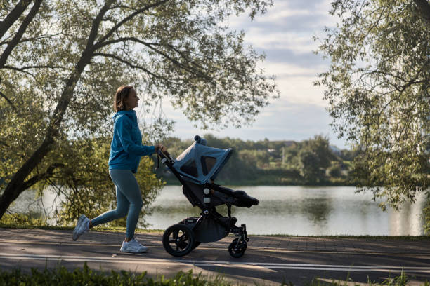 Active mother jogging. Jogging or power walking woman with a baby stroller in morning. Mother with child in stroller running. stock photo