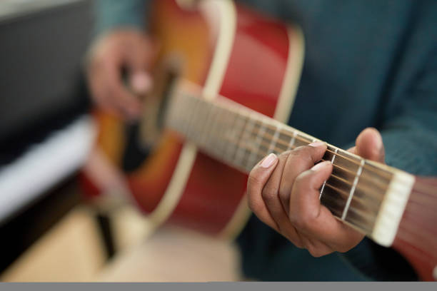 Close-up of student holding the guitar and learning the chords to play the melody during lesson
