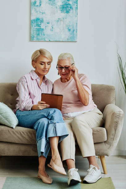 daughter helping senior woman with tablet - grandmother senior adult child multi generation family imagens e fotografias de stock