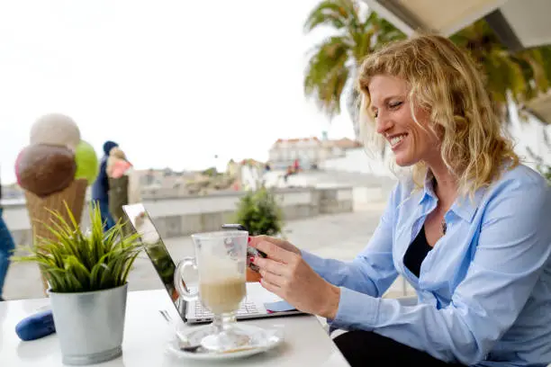 Woman working from a beach terrace, in a smartphone zoom meeting, digital nomad