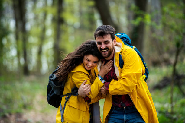 istock Happy couple in raincoats having fun while holding hands and spinning in nature 1391100896