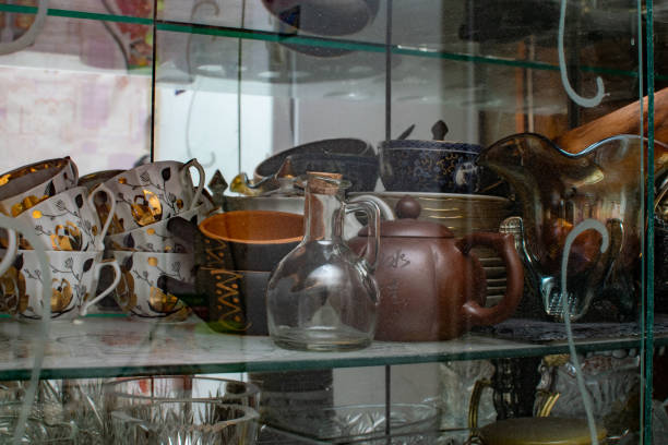 Various crockery under glass in a sideboard, plates and mugs in an old cupboard, a set and set of props for filming and preparing food and drinks, original vessels stock photo