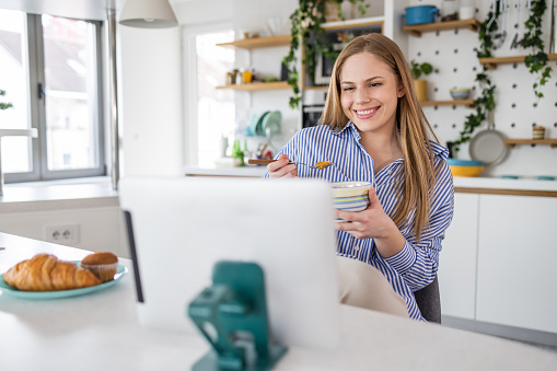 Beautiful woman having breakfast and looking at the tablet