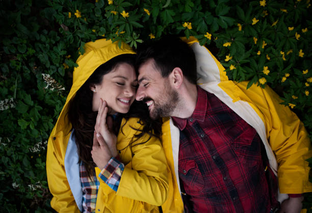 Happy affectionate couple in raincoats enjoying in nature stock photo