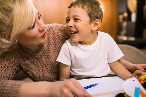 A cute boy and his mom are having fun making chicks out of paper at Easter