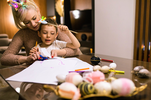 A cute boy and his mom are having fun making chicks out of paper at Easter