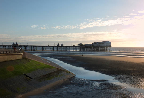 view of blackpool north pier at sunset with the promenade and beach illuminated by evening sunlight - north pier imagens e fotografias de stock