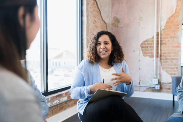 female counselor gestures and talks to unrecognizable group - chinese ethnicity latin american and hispanic ethnicity multi ethnic group business person imagens e fotografias de stock