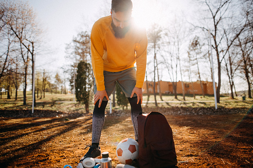Young male football player is getting ready for his outdoor training