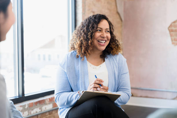 Manager smiles uncertainly at unseen team member When the unseen team member speaks, the mid adult female manager smiles uncertainly. mental health professional stock pictures, royalty-free photos & images