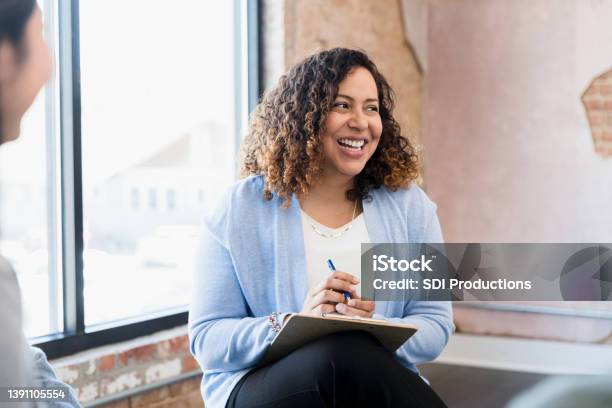 Manager Smiles Uncertainly At Unseen Team Member Stock Photo - Download Image Now - Mental Health Professional, Portrait, Candid