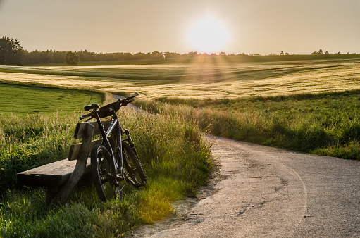 A mountain bike leans against a bench on a sunny evening on a cycle path in the Aartal im Taunus