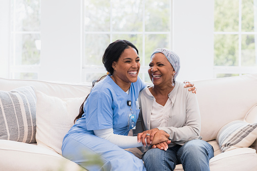 La enfermera de salud en el hogar y la paciente femenina se abrazan y ríen juntas photo