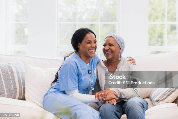 Home Health Nurse And Female Patient Embrace And Laugh Together Stock Photo - Download Image Now