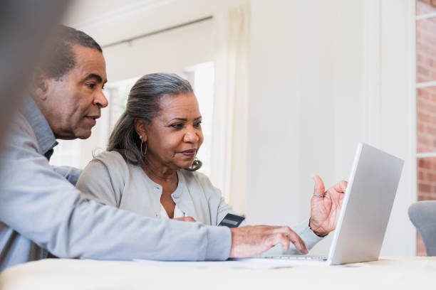 Senior man assists wife with online purchase
