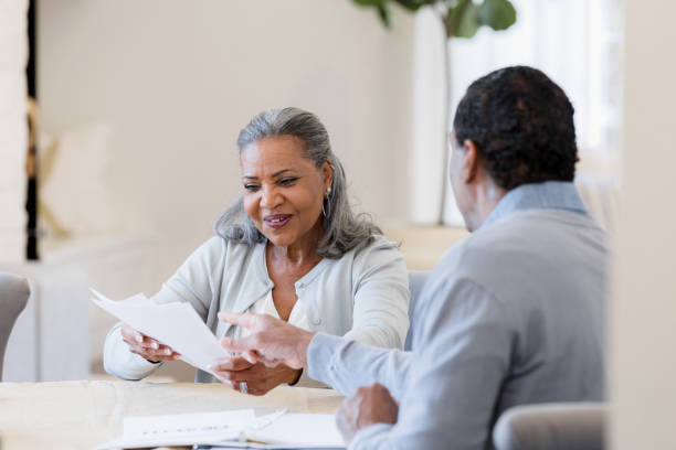 Senior woman smiles as unrecognizable male insurance agent explains paperwork