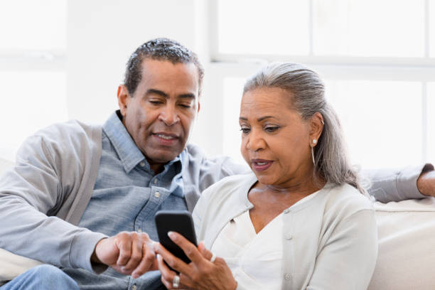 istock Senior husband helps wife with mobile apps on phone 1391107088