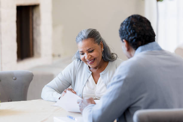 istock Senior woman smiles as unrecognizable male lawyer explains documents 1391107105
