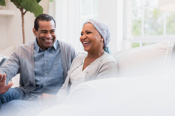 Senior couple smiles and laughs at joke Sitting on their sofa at home, the senior adult couple smiles and laughs at a joke. 60 69 years stock pictures, royalty-free photos & images