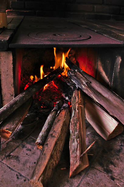 Wood stove with coffee pot on fire and coals on logs