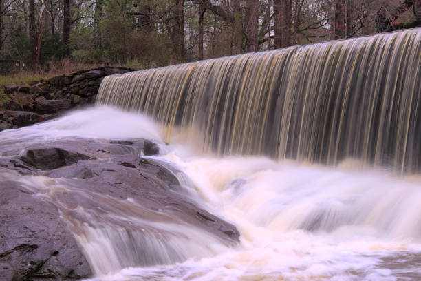 Historic Yates Mill Dam Long exposure shot of the Historic Yates Mill Dam overflowing after a severe downpour. water wheel stock pictures, royalty-free photos & images