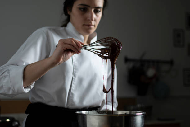 Female confectioner preparing chocolate sauce stock photo