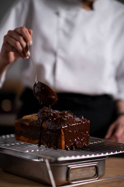 istock Female baker pouring chocolate sauce on cake 1391110169