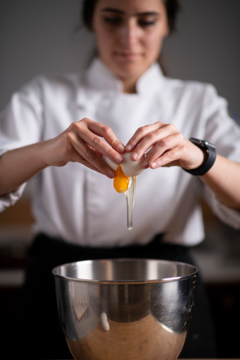 Close up of woman chef breaking egg and making brownie.