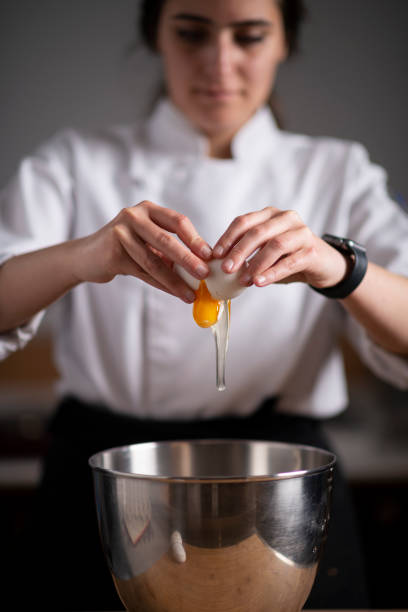 Close up of woman chef breaking egg and making brownie stock photo