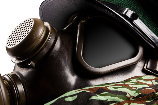 Gas Mask with uniform cap on a camouflage fabric.