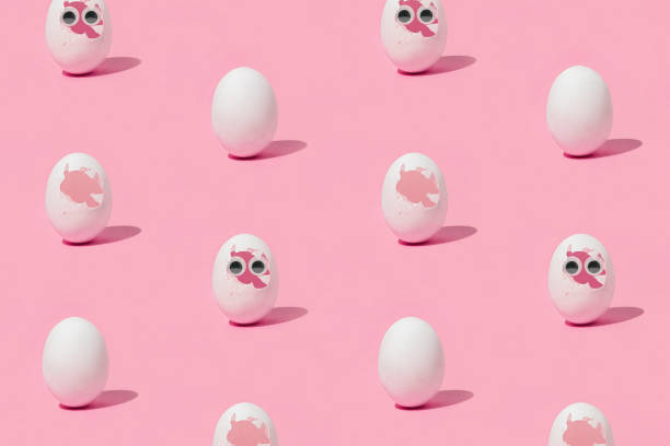 istock Minimal Easter pattern with white whole eggs, broken eggs and eggs with eyes on isolated pastel pink background. Sun and shadows. Concept of new life, beginning, origin or birth. Abstract texture. 1391113760