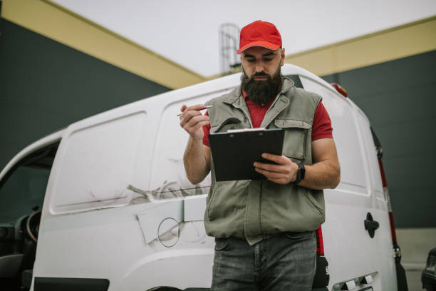 istock Postman writing on his clipboard in front of delivery van 1391113906
