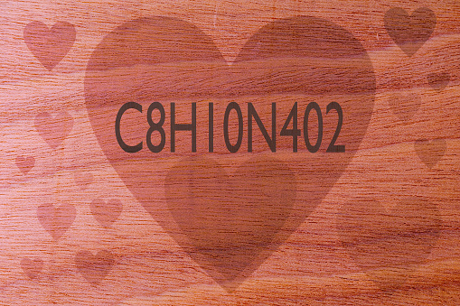 Coffee chemical formula C8H10N4O2 with hearts on a wooden background. Coffee love concept. Conceptual backdrop