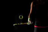 Tennis ball bouncing on racket. Dirt or magnesium dust dots visible in the air. Female player holding racket