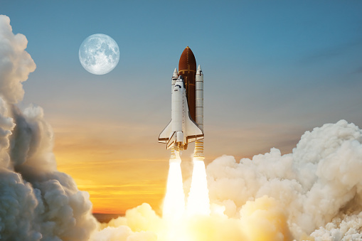 Spaceship lift off. Space shuttle with smoke and blast takes off into space on a background of a sunset with a full moon in the sky. Elements of this image furnished by NASA.