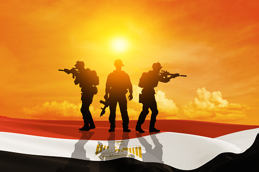 Silhouette of a soliders against the sunrise and egyptian flag. Concept - armed forces of Egypt. Egypt celebration. Greeting card for Independence day, Memorial Day, Armed forces day.