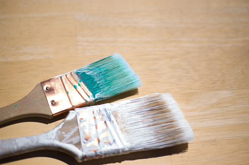 Two Used Paintbrushes: One Turquoise, One White