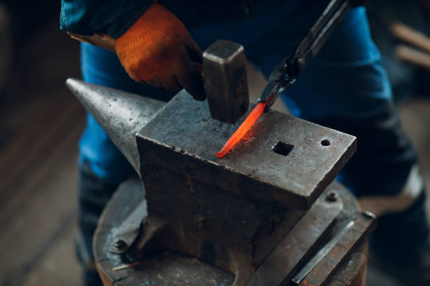istock Blacksmith forges and makes metal detail with hammer and anvil at forge 1391129601