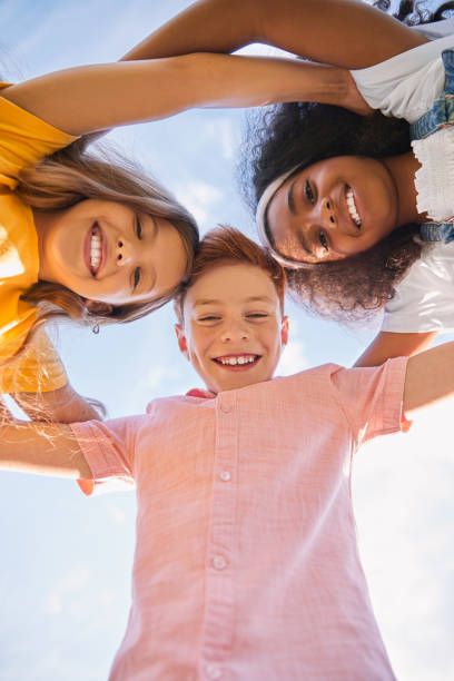istock Happy diverse kids hugging against sky 1391129681