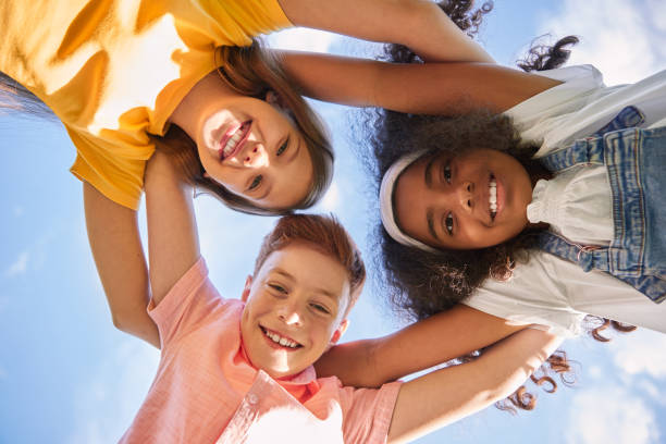 istock Happy kids hugging against blue sky 1391129692