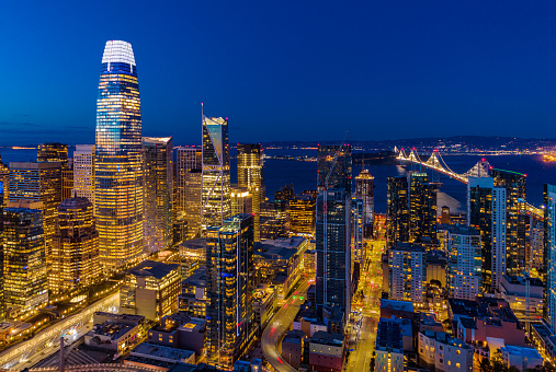 Downtown San Francisco aerial view at dusk with the Bay Bridge and San Francisco Bay in the background.