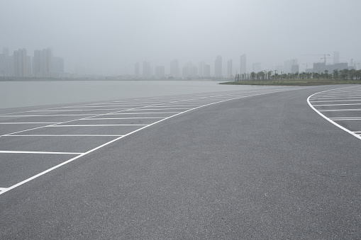 Empty parking spaces and distant urban buildings in haze weather