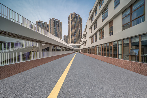 An empty asphalt road passes through the modern buildings on both sides