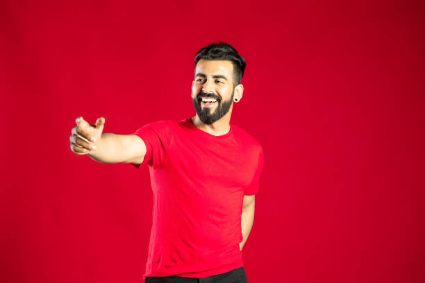 istock Look over there! man pointing away and smiling on red background. 1391139337