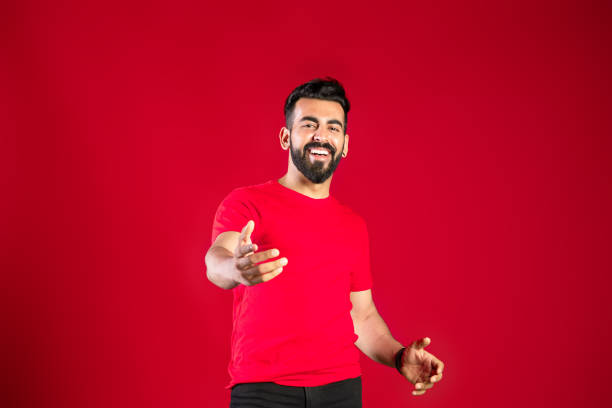 Modern man pointing at camera isolated on red background. stock photo