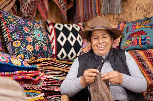 Mujer peruana tejiendo lana de alpaca bebé en una tienda de artesanías photo