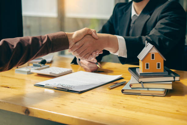 istock Sales representatives shake hands with customers and offer home purchase contracts to purchase current homes and leases offer home owners projects upon signing of contact with insurance. 1391145051
